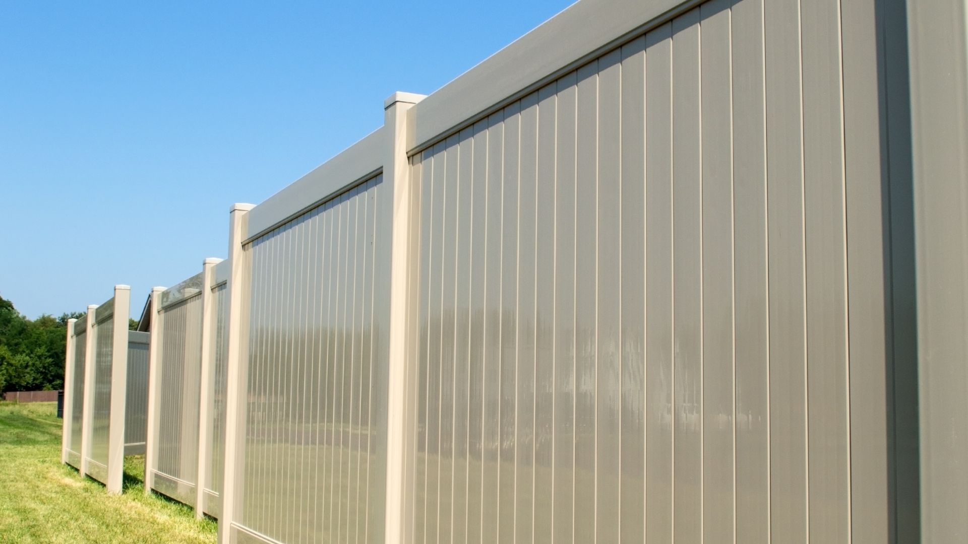 A row of fenced in grass with a blue sky in the background