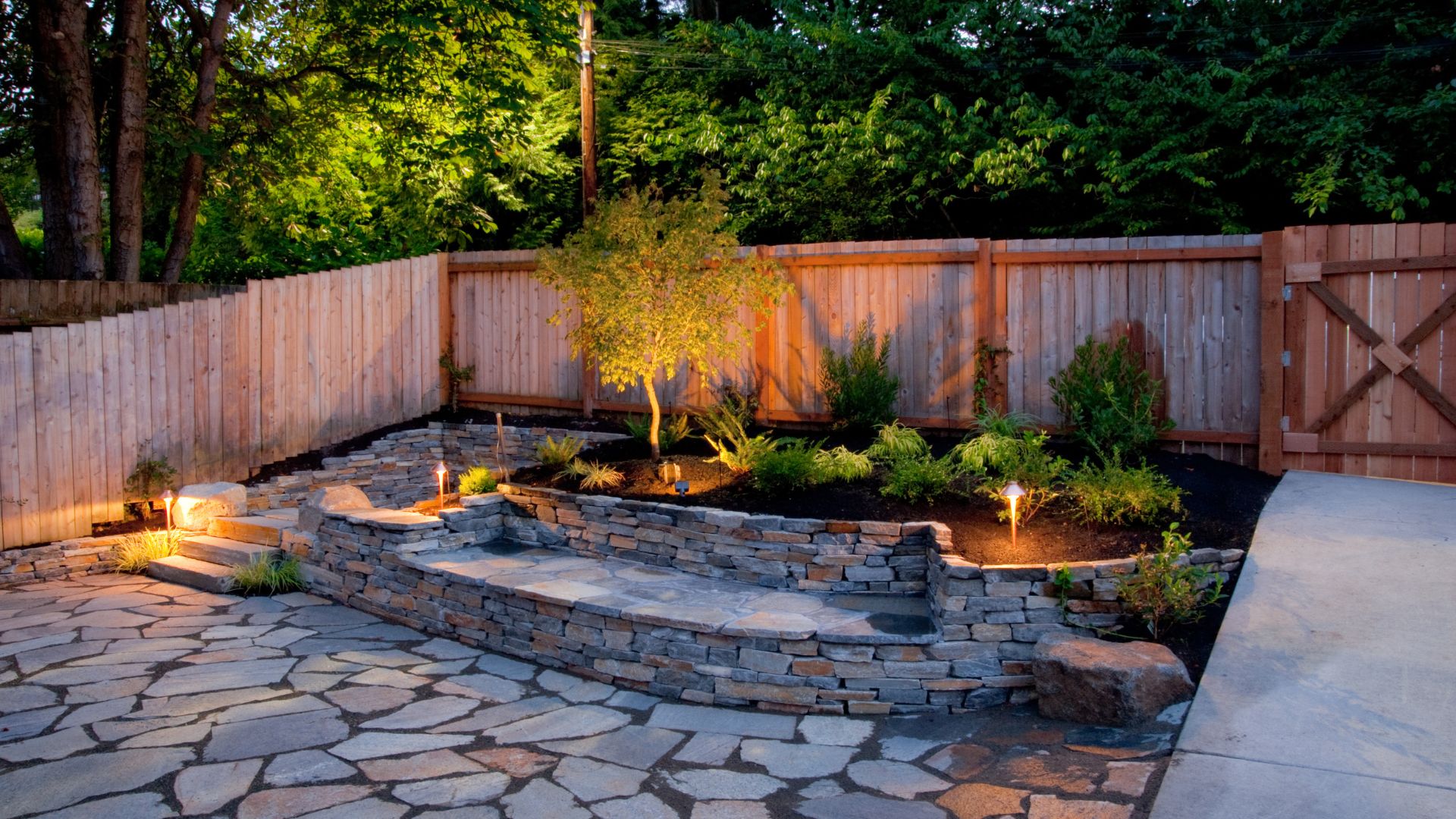 A backyard with a stone patio and a wooden fence