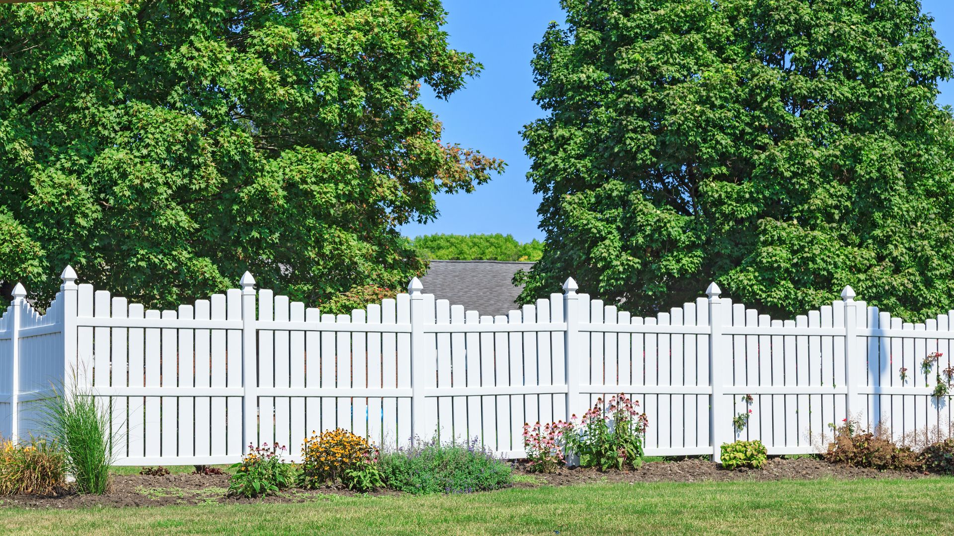 A white picket fence in front of some trees