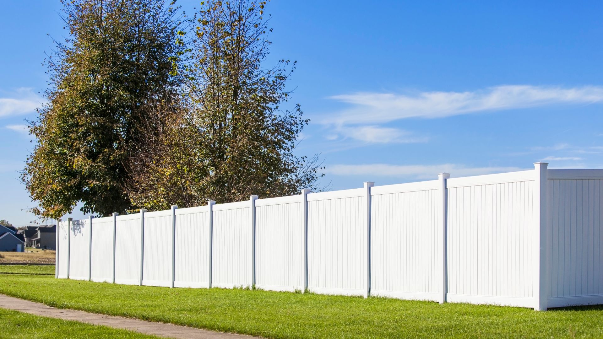 A white fence in front of a green field