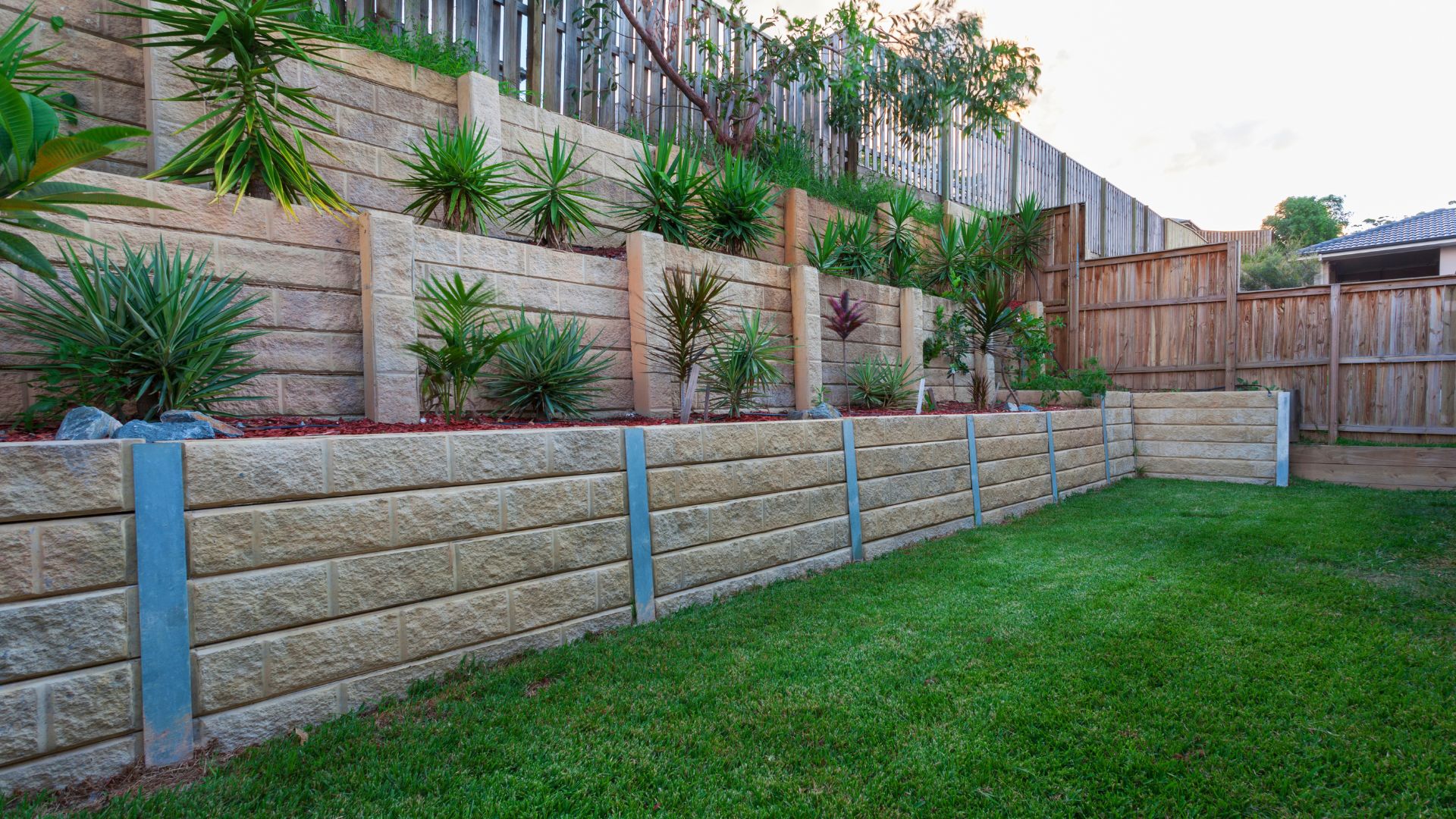 A backyard with a retaining wall and grass