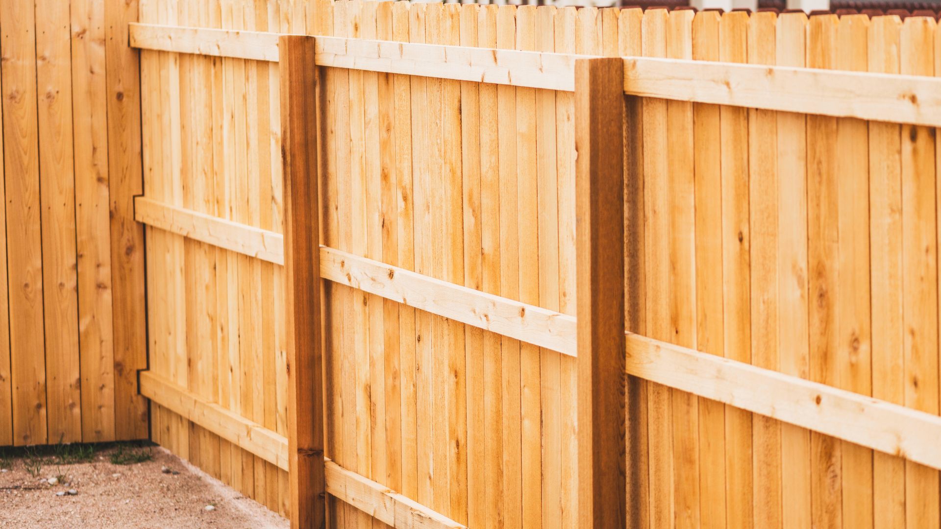 A wooden fence with a cat sitting on top of it